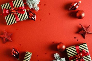 Yeni yıl kartı tasarımı. Noel hediyeleri, köknar dalları, kırmızı toplar ve yıldızlarla bezenmiş düz bir kompozisyon.