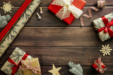 Hediye kutularından yapılmış Noel çerçevesi, ambalaj kağıdı, kırsal ahşap masadaki süslemeler. Klasik Noel arkaplanı.