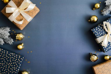 Hediye kutularıyla Noel kompozisyonu, köknar dalları, koyu mavi arka planda altın takılar. Üst manzara, düz yatış. Xmas pankart modeli, eski kart şablonu