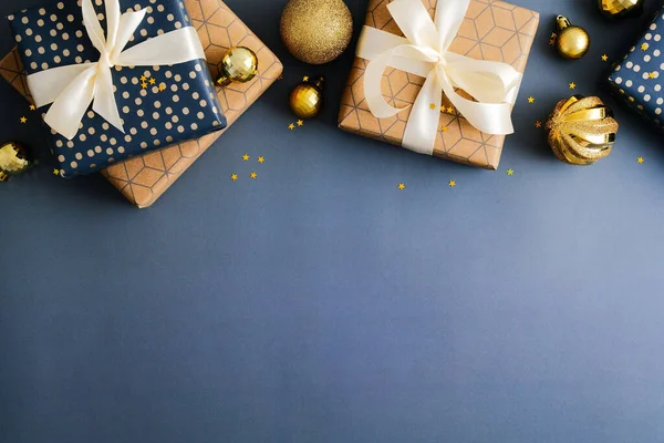 ギフトボックスと濃い青の背景に金色のボールで作られたクリスマスフレームの上の国境 フラットレイアウト トップビュー コピースペース メリークリスマスとハッピーニューイヤーバナーデザイン — ストック写真