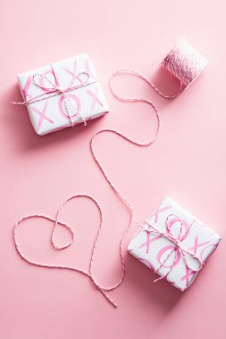 Pembe arka planda hediye kutuları ve kalp şeklinde kurdele. Sevgililer Günü kompozisyonun kutlu olsun..