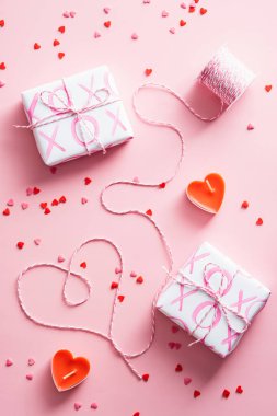 Happy Valentines Day concept. Vertical banner with gifts, heart-shaped ribbon and confetti on pink background.