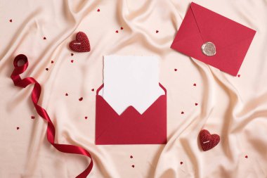 Red envelope with blank paper, red ribbon, hearts on silk. Happy Valentines Day, wedding concept.