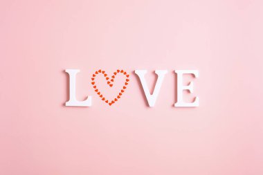 Word love with a heart instead of the letter O on a pink background. Happy Valentine's Day concept