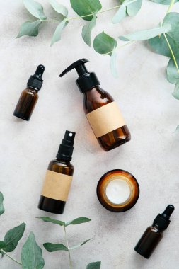 Kehribar cam kozmetik şişeler ve okaliptüs yaprakları taş masa manzarasında. Doğal organik güzellik ürünleri seti. Cilt bakımı kavramı.