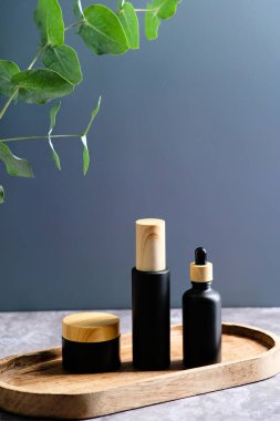 Siyah ve ahşap kozmetik kapları koyu mavi arka planda. Güzellik ürünleri ambalaj tasarımı.
