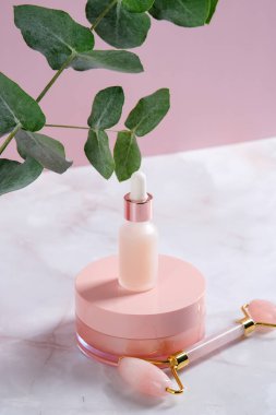 Pembe kozmetik kaplar ve mermer masada yüz silindiri. Yüz bakımı konsepti. Güzellik ürünleri ambalaj tasarımı