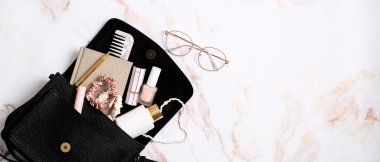 Mermer taş masada kozmetik ve aksesuarlı şık kadın meteoroloji çantası. Moda blog afişi tasarımı.