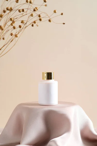 Cosmetic lotion bottle mockup on dais podium with dry flowers on beige background. Natural beauty product design, branding