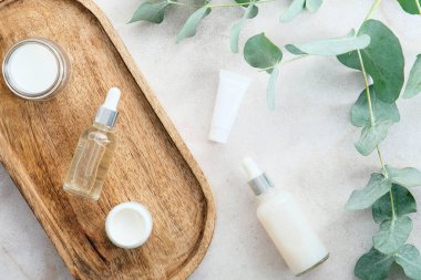 Taş zemin üzerinde okaliptüs yeşil yaprakları olan kozmetik şişeleri ve güzellik ürünleri kapları. Doğal organik cilt ürünleri.