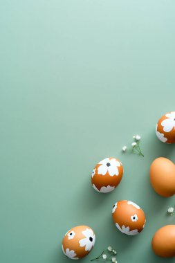 Zarif Paskalya kompozisyonu. Pastel yeşile boyanmış Paskalya yumurtası ve çiçekleri. Düz yerde, üst tarafta. Mutlu Paskalya dikey afişi şablonu.