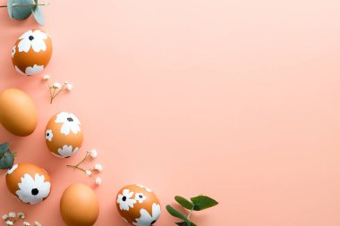 Mutlu Paskalyalar. Paskalya yumurtaları ve pastel pembe arka planda bahar çiçeklerinden yapılmış çerçeve. Düz konum, üst görünüm, kopyalama alanı.