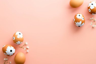 Paskalya yumurtaları ve pastel pembe arka planda çiçekler olan yaratıcı bir düzen. Mutlu Paskalya afişleri. Asgari düzeyde. Düz yatış, üst görünüm