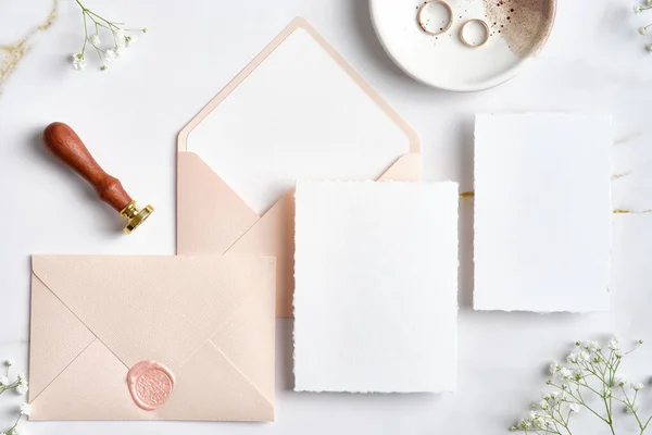 stock image Wedding stationery set. Pastel pink wedding envelopes with wax seal stamp, wedding invitation card, golden rings on stone table. Flat lay, top view, copy space.