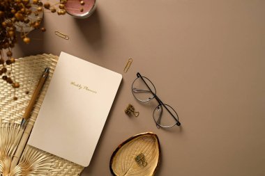 Haftalık ajandası, bardakları, mumu, ofis kağıtları, kurumuş çiçekleri olan rahat ofis masası. Düz yerde, üst tarafta. Sonbahar sonbaharı, hygge, İskandinav tarzı çalışma alanı