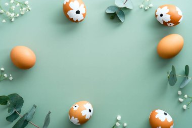Mutlu Paskalya kartı tasarımları. Paskalya yumurtaları, okaliptüs yaprakları ve pastel yeşil arka planda çiçeklerden yapılmış çerçeve..