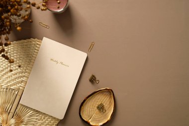 Estetik kadın çalışma alanı üst görüşü. Daire çizelgesi, kurumuş çiçekler, ofis kağıtları, kahverengi arka planda mum. Zarif ofis masası..