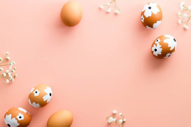 Zarif Paskalya bezi. Paskalya yumurtaları pastel pembe masadaki çiçekleri süsledi. Düz yatış, üst görünüm