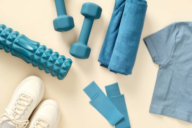 Bej arka plan görünümlü kadın spor giyimli spor aksesuarları