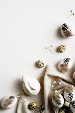 Paskalya düzlüğü kompozisyonu. Beyaz arka planda tüyleri olan Paskalya yumurtaları. Mutlu Paskalya dikey afişi tasarımı.