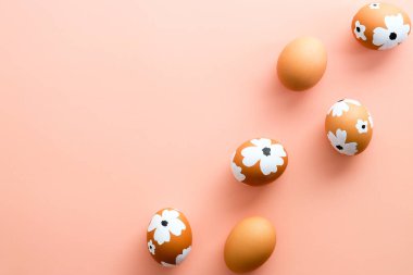 Paskalya yumurtaları pastel pembe arka planda süslü çiçekler. Düz yatış, üst görünüm.