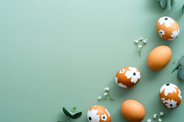 Paskalya düzlüğü kompozisyonu. Çiçekli Paskalya yumurtaları ve pastel yeşil arka planda okaliptüs yaprakları. Mutlu Paskalya kartı tasarımı, şablon.