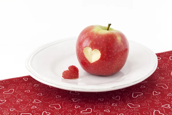 Яблоко с вырезом в форме сердца на скатерти — стоковое фото