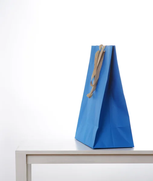 Blå shopping väska på bord Stockbild
