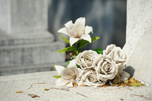 Velha flor falsa branca na sepultura — Fotografia de Stock