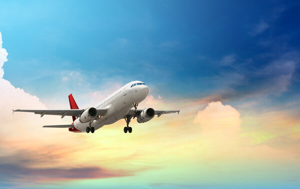 Airplane flying above tropical sea at sunset