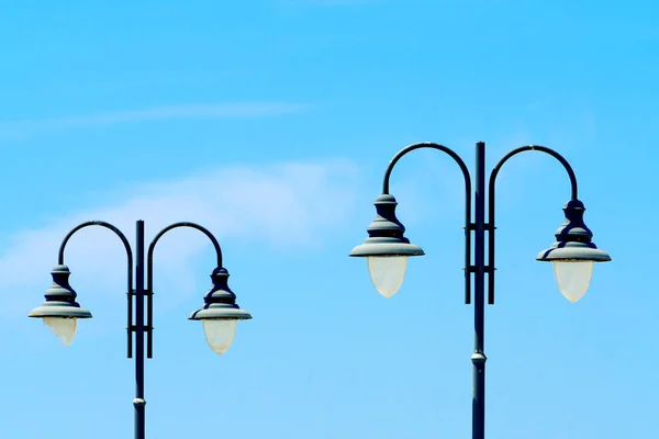 Old-fashioned street lights with broken glass, vintage street lamps close-up against a blue sky on a sunny day