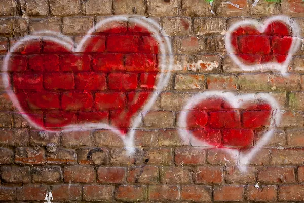 Corações vermelhos pintados em uma parede de tijolo — Fotografia de Stock