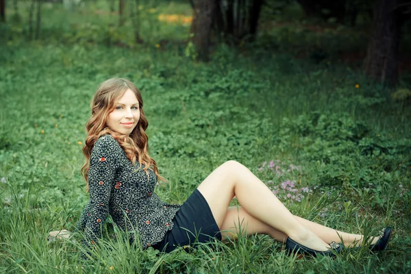 Glückliche Frau auf Gras sitzend — Stockfoto