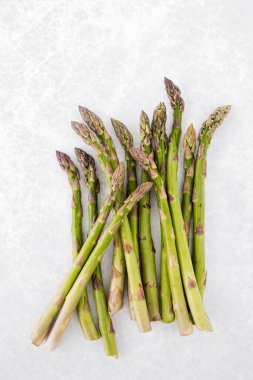 Çiğ ve taze kuşkonmazın üst görüntüsü, arka planda kopyalanmış gri desenli kuşkonmazdan kaynaklanır. Dikey sürüm.