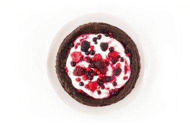Çikolatalı, unsuz, kremalı ve beyaz arka planda dondurulmuş yaz meyveli kek. Üst görünüm.