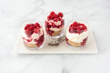 Ahudududulu cheesecake tatlısı, beyaz mermer tahtada üç bardak ve beyaz mermer arka planda fotokopi alanı..