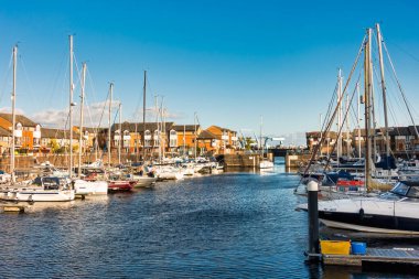 Penarth, Birleşik Krallık - 21 Kasım 2021: Yelkenli tekne, Sunny Autumn Afternoon 'da Cardiff Körfezi' nden Penarth Marina 'ya giriyor. Arka plandaki Cardiff Barrage. Barrage 'da kilitler ve köprüler yer alıyor.