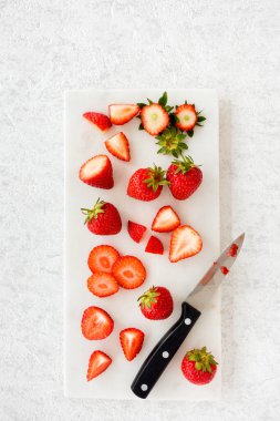 Kesilmiş, dilimlenmiş, ikiye bölünmüş, beyaz mermer üzerine çilek doğranmış mermer kaplama tahtası ve fotokopi alanı. Üst Manzara. Dikey Sürüm.