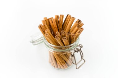 Yüksek kaliteli alba tarçın çubukları beyaz üzerine izole edilmiş cam kavanozun içinde. Yüksek açı görünümü.