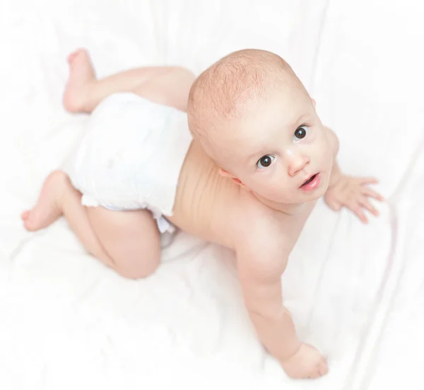 Bebek bezi beyaz yatakta oturmuş