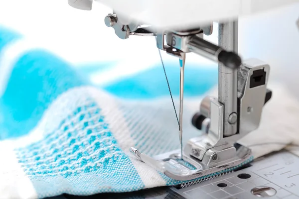 Máquina de coser primer plano con tela azul sobre fondo blanco — Foto de Stock