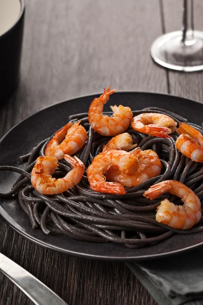 Black italian pasta with shrimps food on dark background