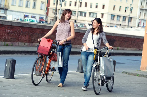 行走在城市与自行车和袋中的两个漂亮女人 — 图库照片