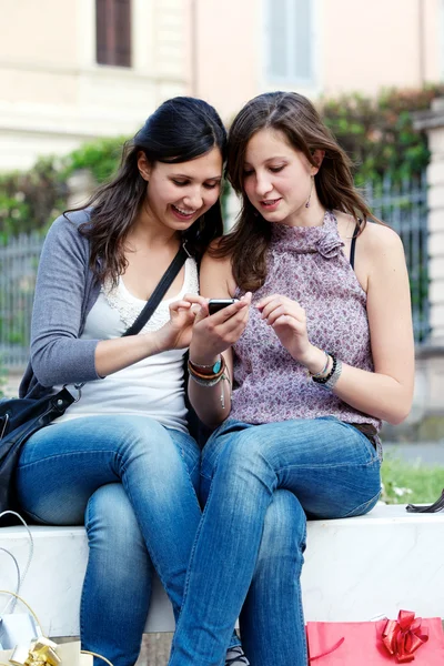 Twee vriendinnen in park met een mobiele telefoon — Stockfoto