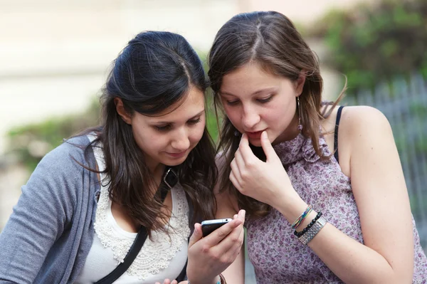 Two girlfriends in park with a mobile phone — Stock Photo, Image