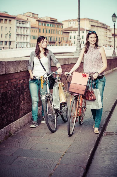 Zwei schöne Frauen, die mit Fahrrädern und Taschen durch die Stadt laufen — Stockfoto