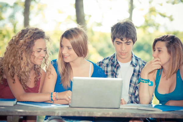 Grupo de jóvenes estudiantes que utilizan el ordenador portátil al aire libre, Italia — Foto de Stock