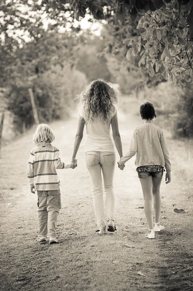 Mooie jonge vrouw met twee kinderen buiten — Stockfoto