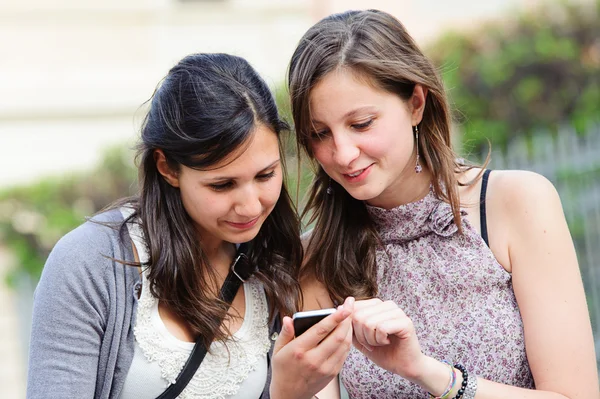 Two shopping girls in park with a mobile phone — Stock Photo, Image