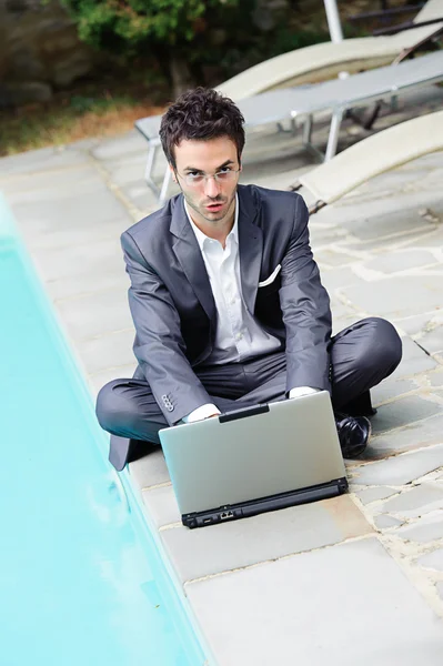 Fiatal üzletember, a medence mellett számítógép — Stock Fotó